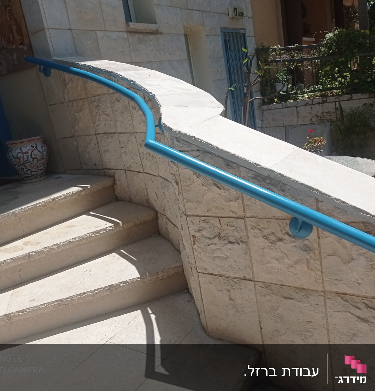 מעקה כחול על קיר אבן ליד מדרגות